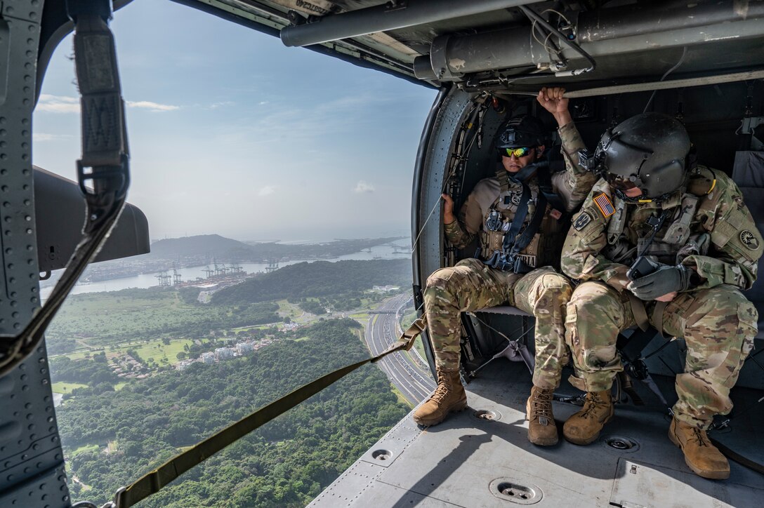 A Panamanian soldier, left, and U.S. Army Sgt. 1st Class Paul A. Bohnert, 1st Battalion, 228th Aviation Regiment crew chief, overlooks Panama City, during PANAMAX-Alpha Phase I, at Panama City, Panama, July 15, 2025. PANAMAX is a joint exercise designed to enhance interoperability among participating nations and strengthen their ability to conduct multinational operations, particularly to defend the Panama Canal. (U.S. Air Force photo by Staff Sgt. Sadie Colbert)