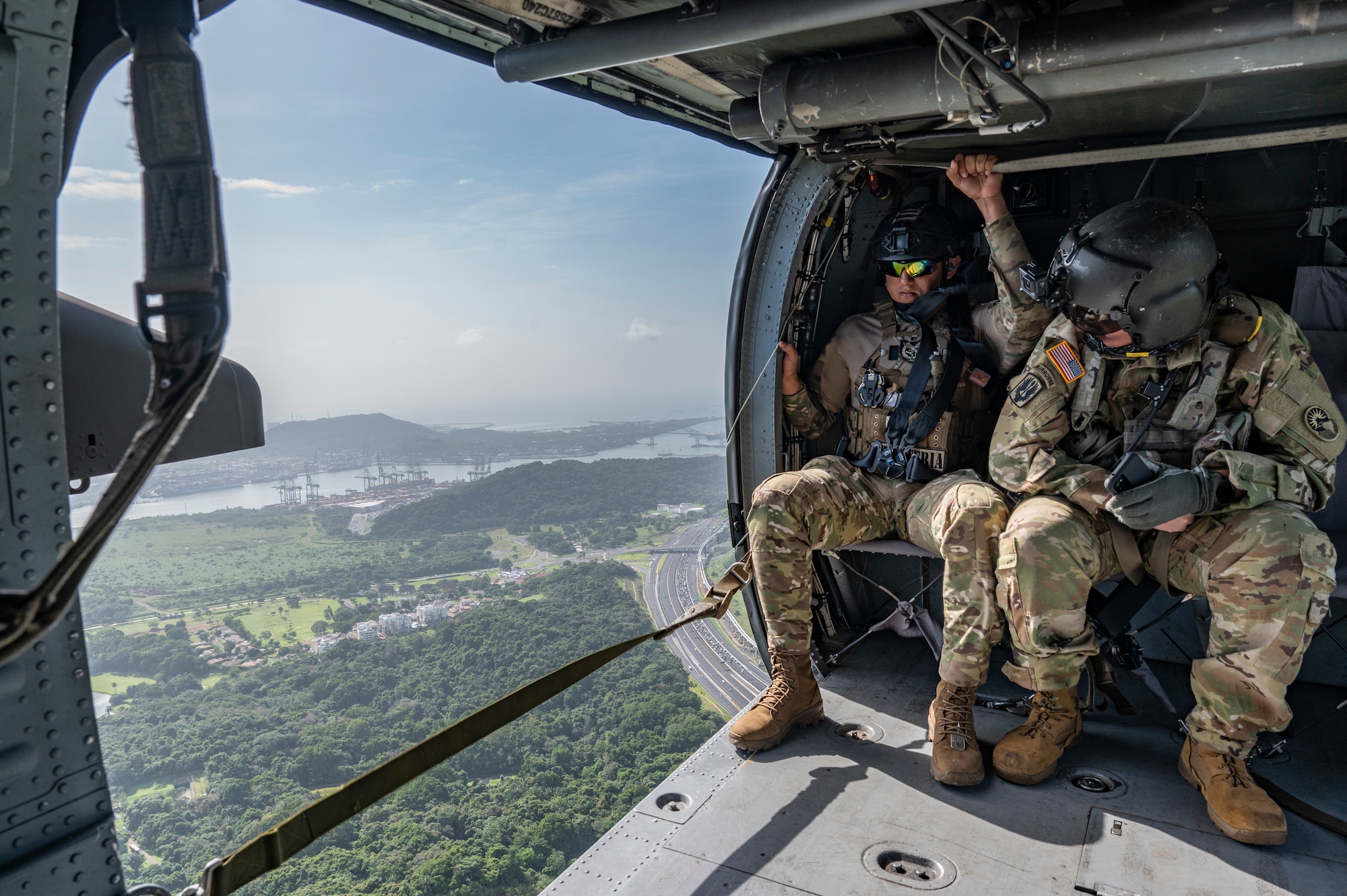 A Panamanian soldier, left, and U.S. Army Sgt. 1st Class Paul A. Bohnert, 1st Battalion, 228th Aviation Regiment crew chief, overlooks Panama City, during PANAMAX-Alpha Phase I, at Panama City, Panama, July 15, 2025. PANAMAX is a joint exercise designed to enhance interoperability among participating nations and strengthen their ability to conduct multinational operations, particularly to defend the Panama Canal. (U.S. Air Force photo by Staff Sgt. Sadie Colbert)