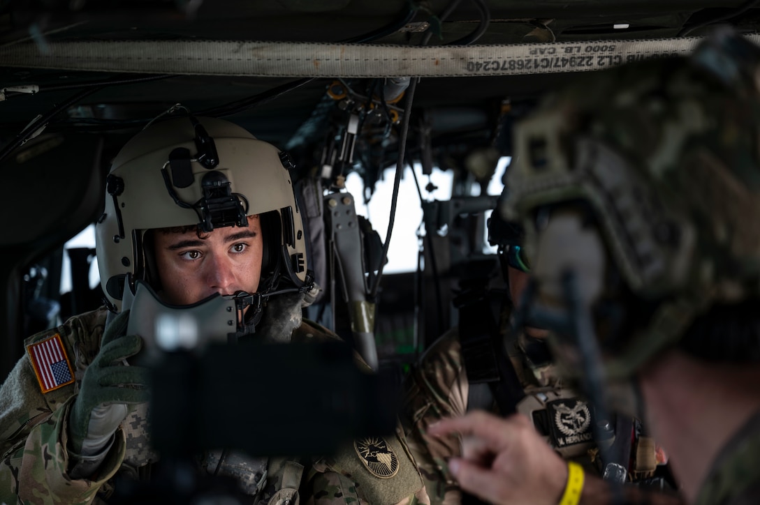 U.S. Army Sgt. Chris Schreerer, 1st Battalion, 228th Aviation Regiment crew chief, speaks with a U.S. Naval Special Warfare operator during PANAMAX-Alpha Phase I, at Panama City, Panama, July 16, 2025. Joint Task Force-Bravo’s UH-60 Blackhawk, assigned to the 1-228th Aviation Regiment, provided overhead support during a bilateral simulated visit, board, search, and seizure training between U.S. and Panamanian special forces units. (U.S. Air Force photo by Staff Sgt. Sadie Colbert)