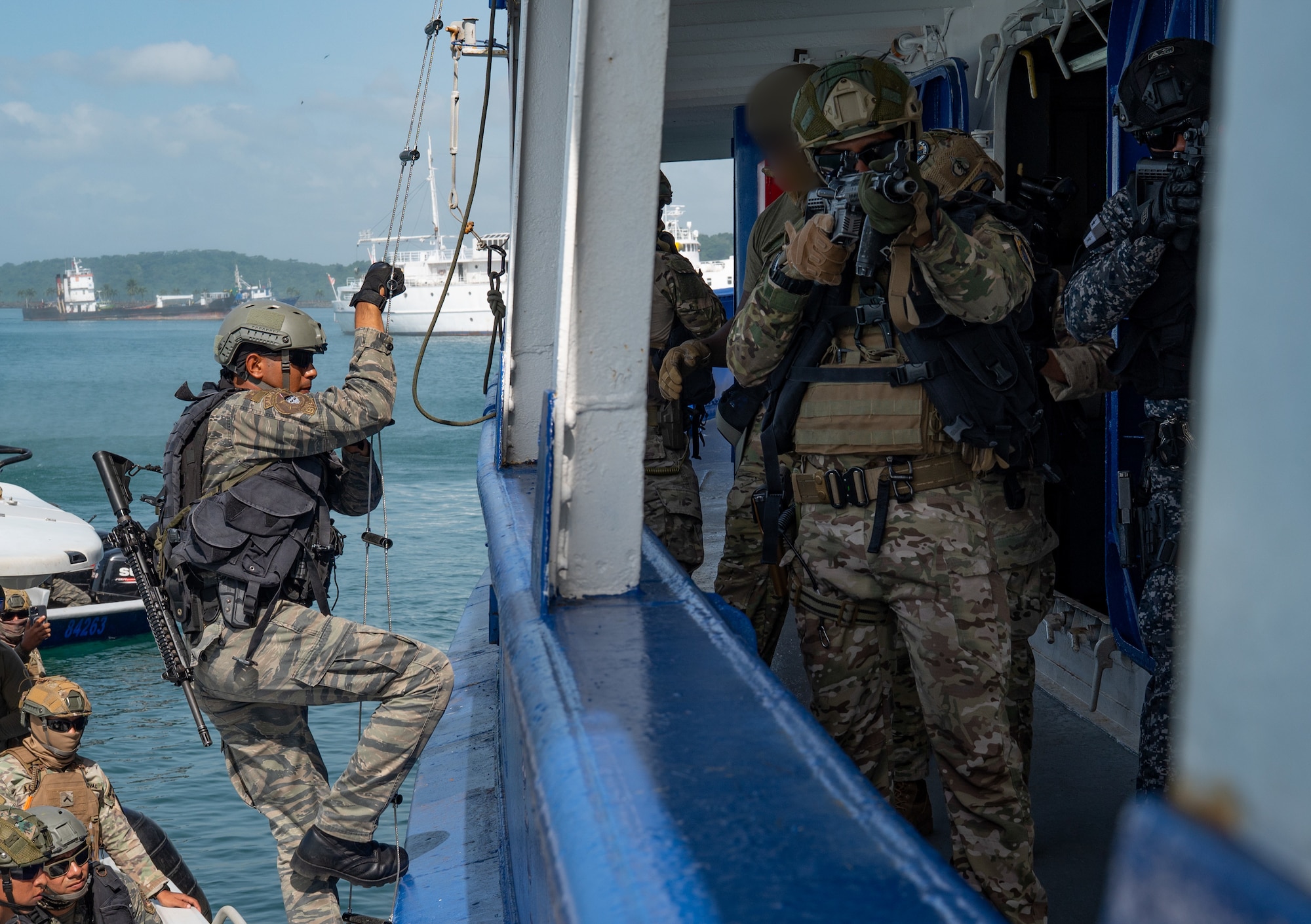 A Panamanian Servicio Nacionales de Fronteras (SENAFRONT) member boards a vessel, while another provides cover during a bilateral simulated visit, board, search, and seizure training between U.S. and Panamanian special forces units, at Panama City, Panama, July 17, 2025. PANAMAX-Alpha Phase I is a joint exercise designed to enhance interoperability among participating nations and strengthen their ability to conduct multinational operations, particularly to defend the Panama Canal. (U.S. Air Force photo by Staff Sgt. Sadie Colbert)
