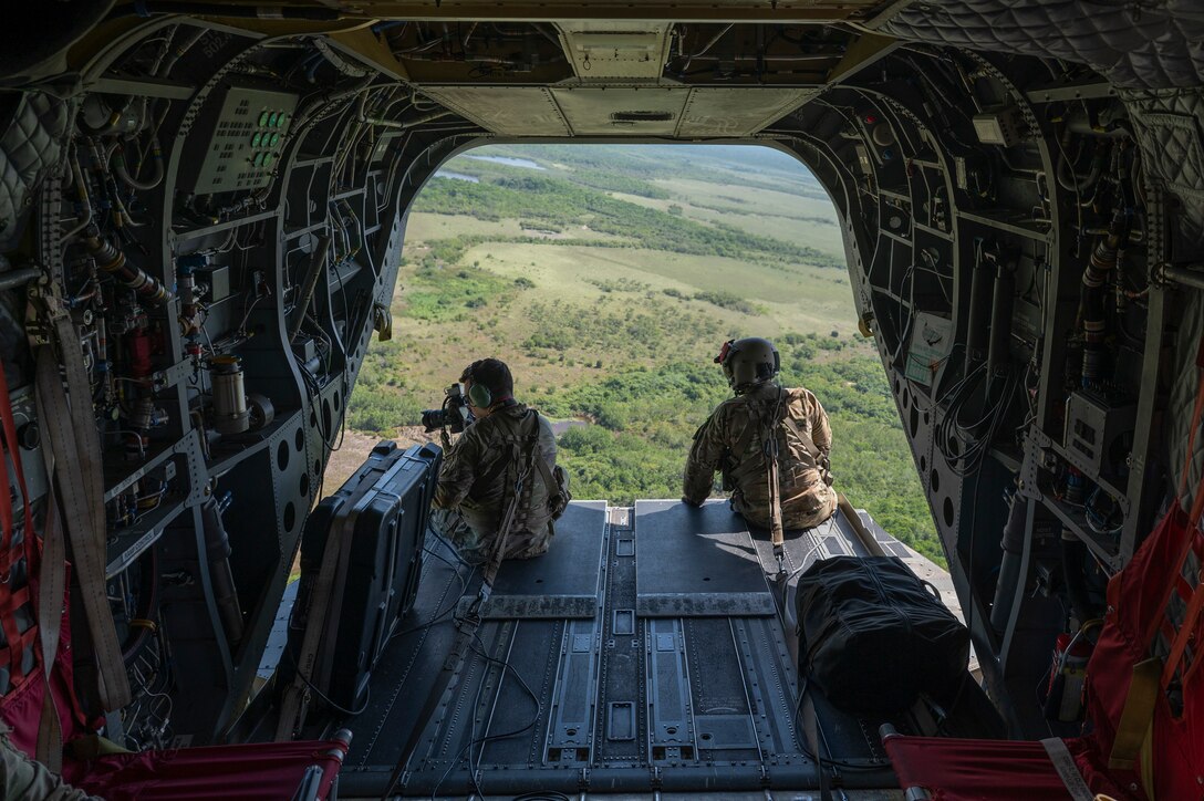 U.S. Army Joint Task Force-Bravo J7 member, left, takes a photo while a CH-47 Chinook crew chief, 1st Battalion, 228th Aviation Regiment, observes in a CH-47 Chinook in Belize during exercise AGILE BEAR, August 2, 2025. Exercises like AGILE BEAR increase our shared readiness to respond to natural disasters and security challenges through multifaceted capabilities ensuring our strength through unity and solidifying U.S. Southern Command's Joint Task Force-Bravo, as the partner of choice in Central America. (U.S. Air Force photo by Staff Sgt. Sadie Colbert)