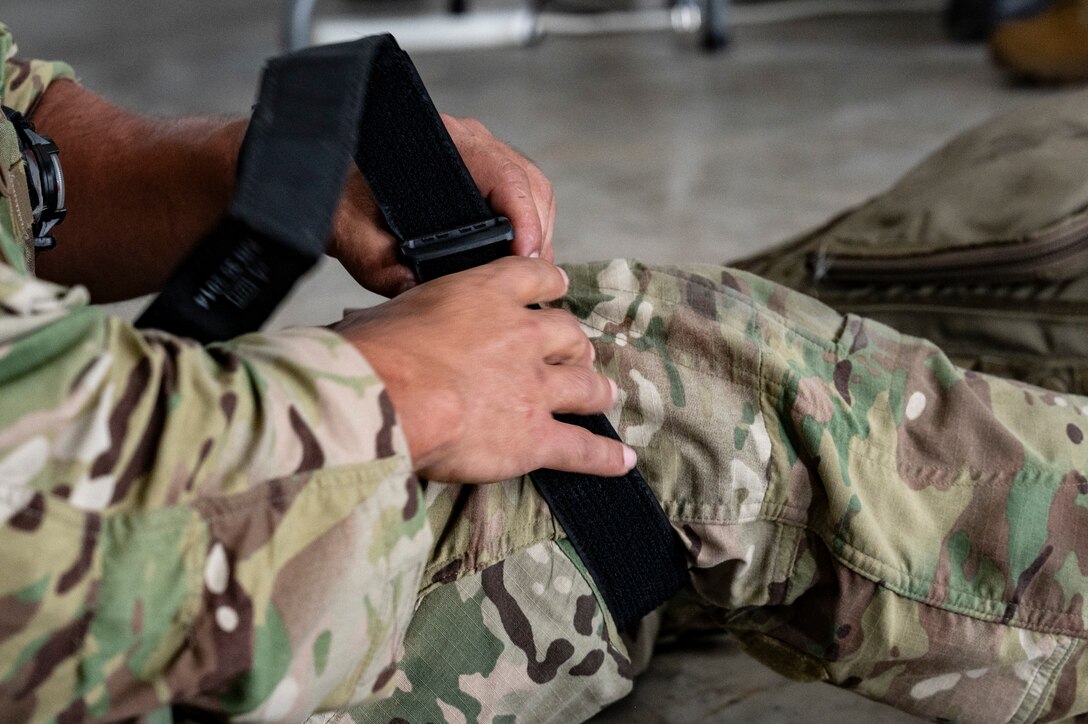 U.S. Air Force Tech. Sgt. Daniel Rodriguez, 100th Operation Support Squadron survival, resistance, evasion and escape instructor out of Mildenhall Air Force Base, England, demonstrates how to use a tourniquet as Belize Defence Force and Belize Coast Guard members observe, during exercise AGILE BEAR 25, Belize City, Belize, Aug. 4, 2025. AGILE BEAR, led by Joint Task Force-Bravo provides critical subject matter expert exchanges in disaster response and counter transnational criminal organization activities preparing U.S. Southern Command’s Situational Assessment Team, 1st Battalion, 228th Aviation Regiment, and Belize and NATO partners for a collaborative response in times of crises. (U.S. Air Force photo by Staff Sgt. Sadie Colbert)
