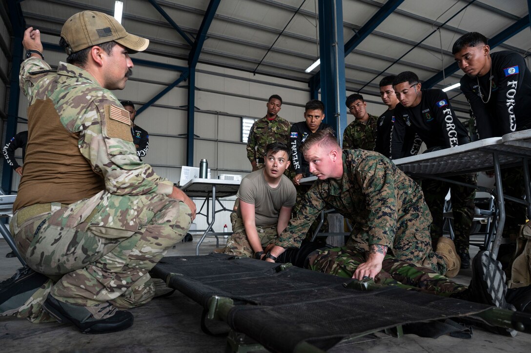 U.S. Air Force Tech. Sgt. Daniel Rodriguez, (left), 100th Operation Support Squadron, survival, resistance, evasion and escape instructor, U.S. Army Sgt. Zachery Quiales, (center), 311th Field Hospital combat medic, and U.S. Marine Corps Gunnery Sgt. Jonathan Vance, (right), Joint Task Force-Bravo firefighter, prepare to transfer a patient during a tactical combat casualty care subject matter expert exchange as part of exercise AGILE BEAR 25, Belize City, Belize, Aug. 4, 2025. Given Central America's high vulnerability to natural disasters, Joint Task Force-Bravo's AGILE BEAR exercise works collaboratively with the British Army Training Support Unit-Belize to equip Belizean forces with the necessary knowledge and resources to lessen the impact of these events. (U.S. Air Force photo by Staff Sgt. Sadie Colbert)