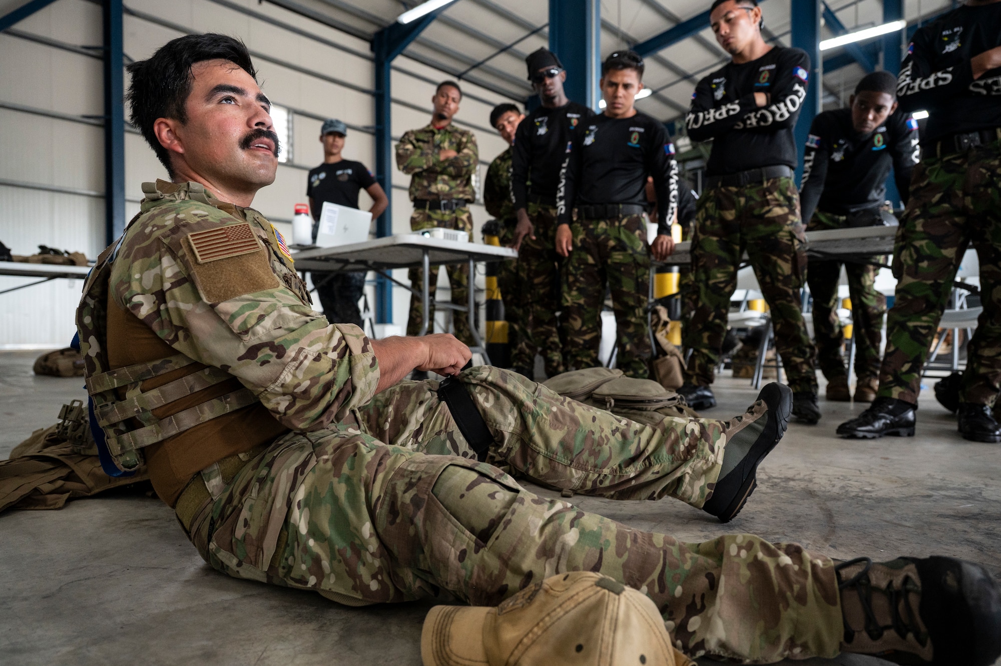 U.S. Air Force Tech. Sgt. Daniel Rodriguez, 100th Operation Support Squadron survival, resistance, evasion and escape instructor out of Mildenhall Air Force Base, England, demonstrates how to use a tourniquet as Belize Defence Force and Belize Coast Guard members observe, during exercise AGILE BEAR 25, Belize City, Belize, Aug. 4, 2025. AGILE BEAR, led by Joint Task Force-Bravo provides critical subject matter expert exchanges in disaster response and counter transnational criminal organization activities preparing U.S. Southern Command’s Situational Assessment Team, 1st Battalion, 228th Aviation Regiment, and Belize and NATO partners for a collaborative response in times of crises. (U.S. Air Force photo by Staff Sgt. Sadie Colbert)