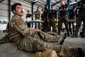 U.S. Air Force Tech. Sgt. Daniel Rodriguez, 100th Operation Support Squadron survival, resistance, evasion and escape instructor out of Mildenhall Air Force Base, England, demonstrates how to use a tourniquet as Belize Defence Force and Belize Coast Guard members observe, during exercise AGILE BEAR 25, Belize City, Belize, Aug. 4, 2025. AGILE BEAR, led by Joint Task Force-Bravo provides critical subject matter expert exchanges in disaster response and counter transnational criminal organization activities preparing U.S. Southern Command’s Situational Assessment Team, 1st Battalion, 228th Aviation Regiment, and Belize and NATO partners for a collaborative response in times of crises. (U.S. Air Force photo by Staff Sgt. Sadie Colbert)