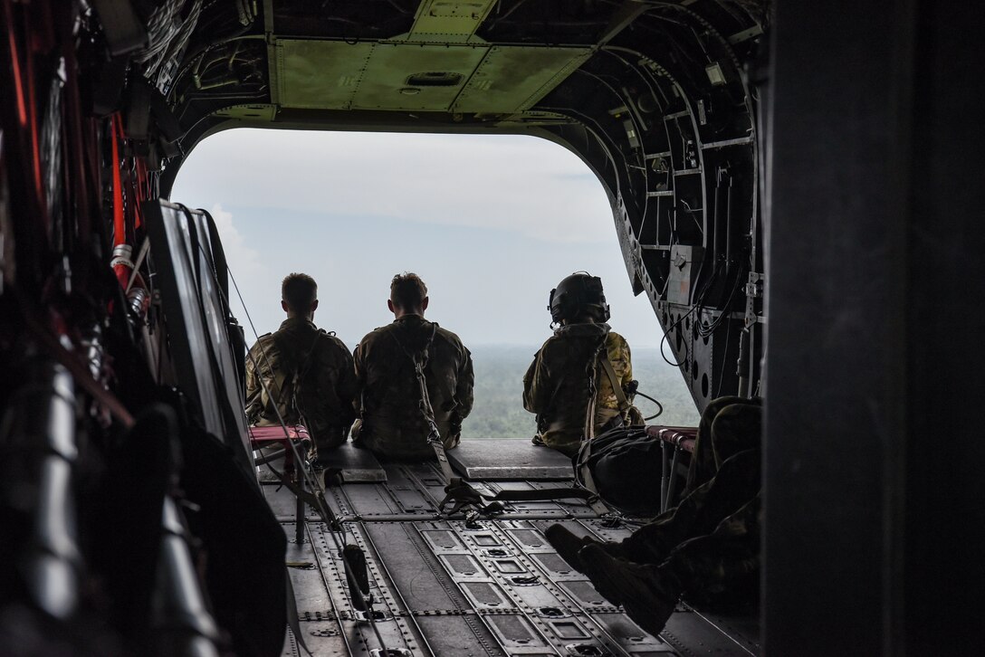 Two British Army Training Support Unit Belize (BATSUB) members, (left), and a U.S. Army 1st Battalion, 228th Aviation Regiment crew chief, sit on a CH-47 Chinook ramp, over Belize, Aug. 5, 2025. As U.S. Southern Command’s rapid response element in Central America, Joint Task Force-Bravo provides a unique and essential capability in enabling our partner nations to proactively confront threats to their security through exercises like AGILE BEAR, preparing our teams to respond to crises in the joint operational area. (U.S. Air Force photo by Tech. Sgt. Dylan Rossitto)
