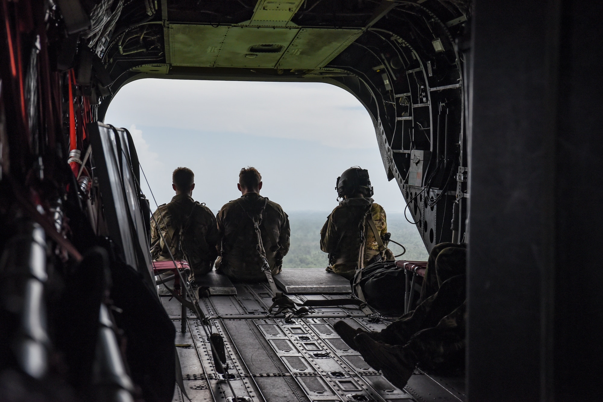 Two British Army Training Support Unit Belize (BATSUB) members, (left), and a U.S. Army 1st Battalion, 228th Aviation Regiment crew chief, sit on a CH-47 Chinook ramp, over Belize, Aug. 5, 2025. As U.S. Southern Command’s rapid response element in Central America, Joint Task Force-Bravo provides a unique and essential capability in enabling our partner nations to proactively confront threats to their security through exercises like AGILE BEAR, preparing our teams to respond to crises in the joint operational area. (U.S. Air Force photo by Tech. Sgt. Dylan Rossitto)