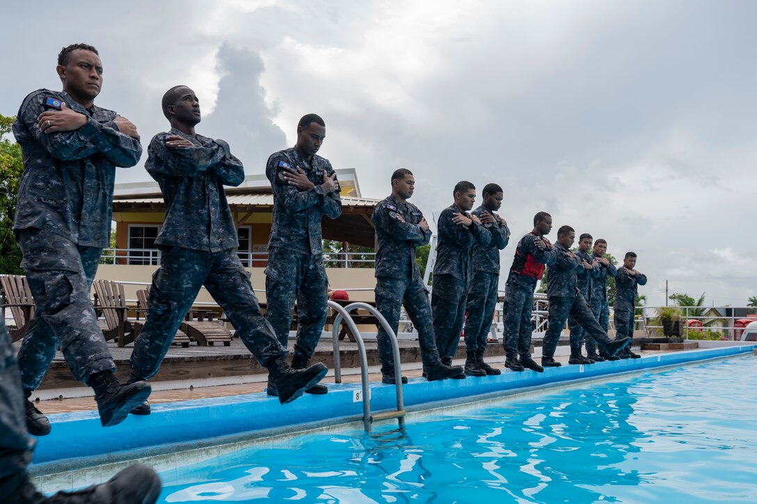 Belize Coast Guard members step into a pool in preparation for helocast during AGILE BEAR 25, at Belize City, Belize, Aug. 5, 2025. Subject matter expert exchanges with partner forces focused on specialized skills such as small Unmanned Aircraft Systems (sUAS) operations, combatives, Tactical Combat Casualty Care (TCCC), Helocast procedures, and conducting troop movements to remote locations. (U.S. Air Force photo by Staff Sgt. Sadie Colbert)