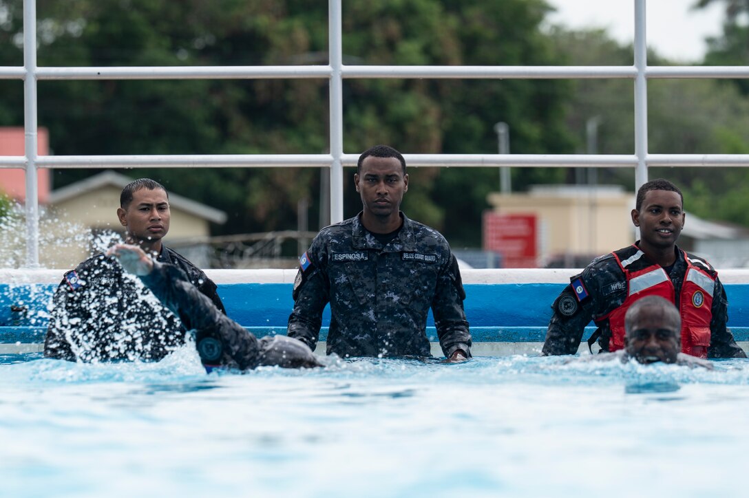 Three Belize Coast Guard members observe the hundred meter swim prior to helocast practice during AGILE BEAR 25, at Belize City, Belize, Aug. 5, 2025. In addition to a distance swim, Belize Defence Force, BCG, and U.S. service members had to tread water for five minutes to showcase their swimming techniques. The exercise aims to strengthen the readiness of U.S. and partner nation forces to respond effectively during a disaster and in countering transnational criminal organizations through various subject matter expert exchanges. (U.S. Air Force photo by Staff Sgt. Sadie Colbert)