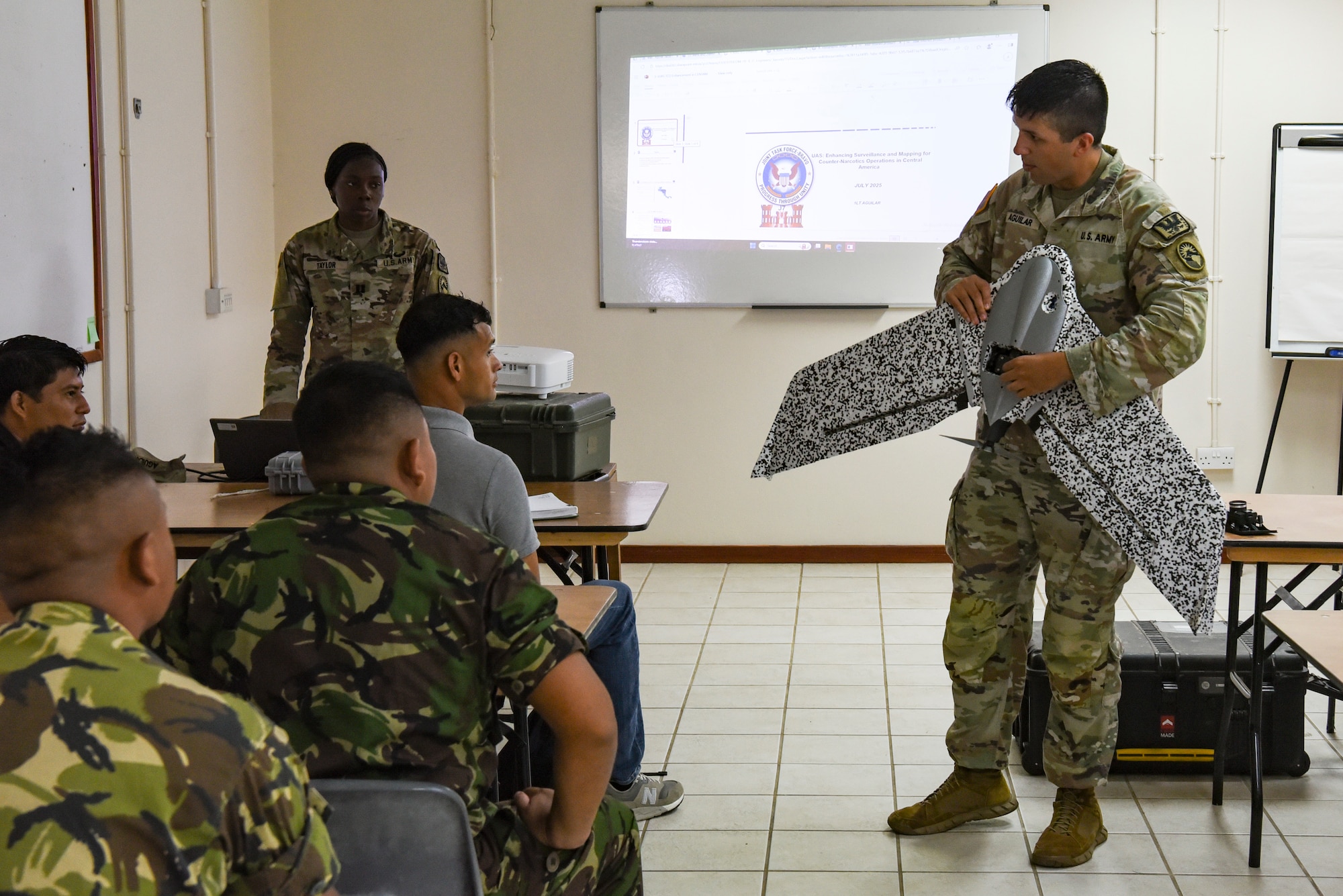 U.S. Army 1st Lt. Jacob Aguilar, Joint Task Force-Bravo J7 engineering project officer, explains parts of a small, unmanned aircraft system (sUAS) with Belize Defence Force and Belize Coast Guard members during exercise AGILE BEAR 25, Belize City, Belize, Aug. 4, 2025. AGILE BEAR, led by JTF-Bravo provides critical subject matter expert exchanges in disaster response and counter transnational criminal organization activities preparing U.S. Southern Command’s Situational Assessment Team, 1st Battalion, 228th Aviation Regiment, and Belize and NATO partners for a collaborative response in times of crises. (U.S. Air Force photo by Tech. Sgt. Dylan Rossitto)