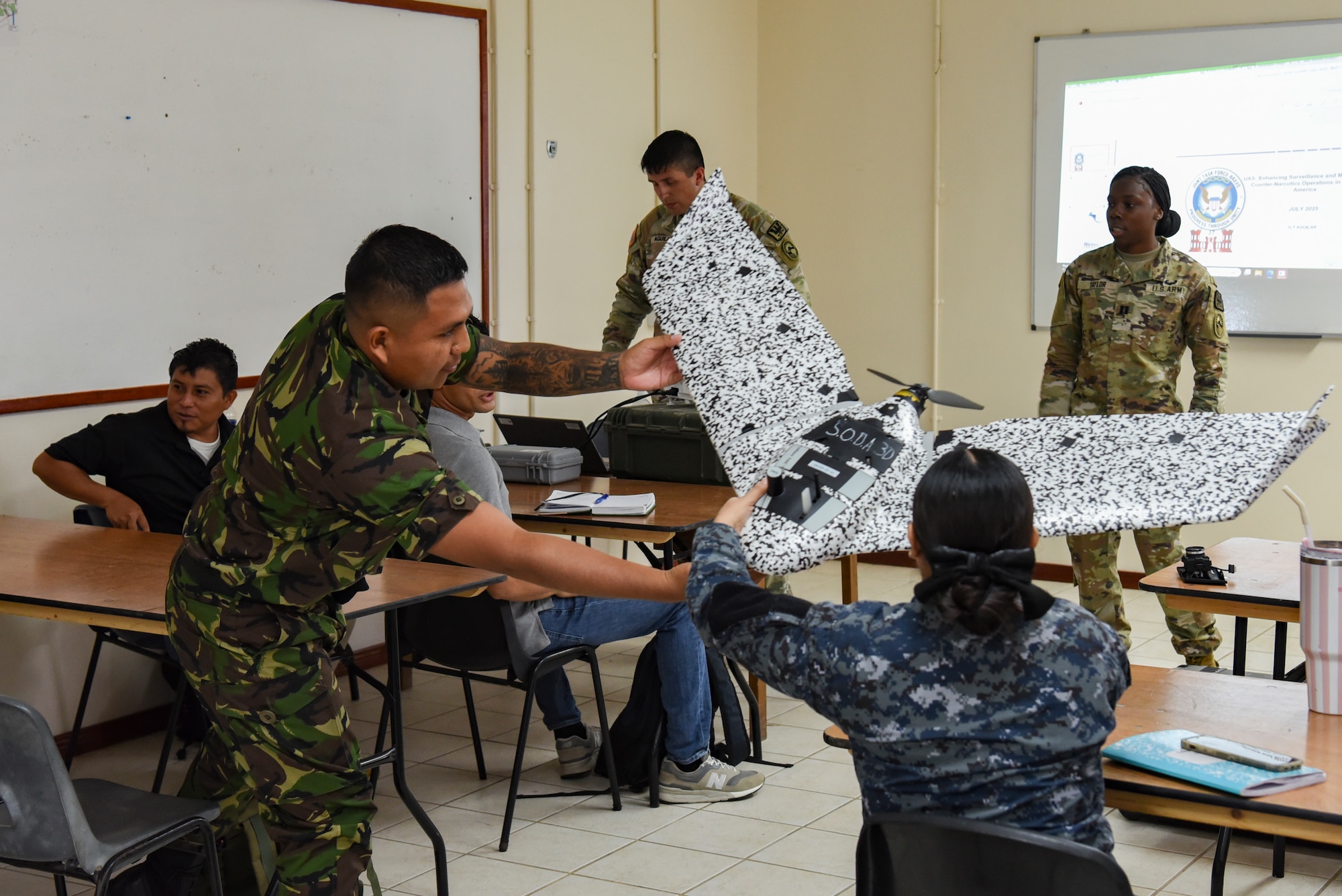 Belize Defence Force and Belize Coast Guard members look at a small, unmanned aircraft system (sUAS) during exercise AGILE BEAR 25, Belize City, Belize, Aug. 4, 2025. During the course, participants learned about the advantages and uses of sUASs, aiding in the collection of data without putting service members in harm’s way. AGILE BEAR, led by Joint Task Force-Bravo provides critical subject matter expert exchanges in disaster response and counter transnational criminal organization activities preparing U.S. Southern Command’s Situational Assessment Team, 1st Battalion, 228th Aviation Regiment, and Belize and NATO partners for a collaborative response in times of crises. (U.S. Air Force photo by Tech. Sgt. Dylan Rossitto)