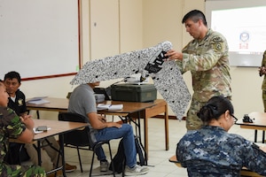 U.S. Army 1st Lt. Jacob Aguilar, Joint Task Force-Bravo J7 engineering project officer, explains parts of a small, unmanned aircraft system (sUAS) during exercise AGILE BEAR 25, Belize City, Belize, Aug. 4, 2025. AGILE BEAR, led by JTF-Bravo provides critical subject matter expert exchanges in disaster response and counter transnational criminal organization activities preparing U.S. Southern Command’s Situational Assessment Team, 1st Battalion, 228th Aviation Regiment, and Belize and NATO partners for a collaborative response in times of crises. (U.S. Air Force photo by Tech. Sgt. Dylan Rossitto)