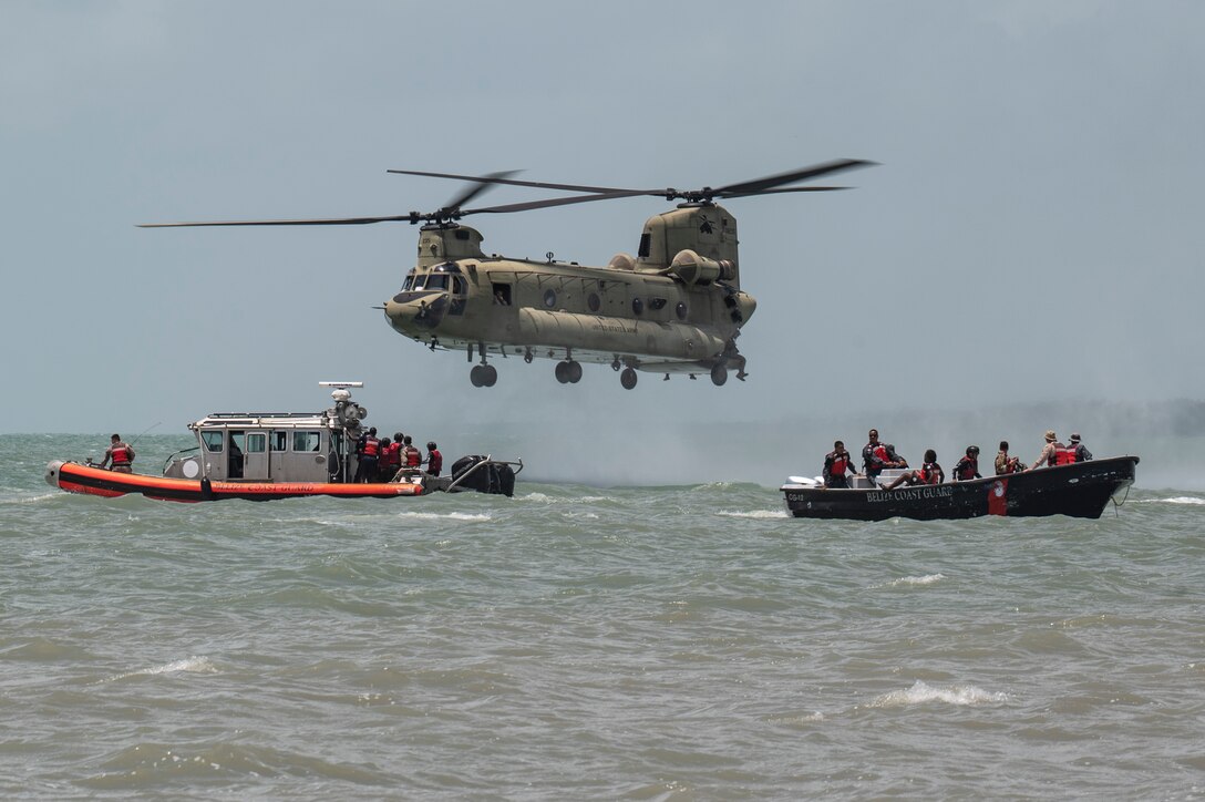 A CH-47 Chinook assigned to 1st Battalion, 228th Aviation Regiment out of Soto Cano Air Base, Honduras, hovers near Belize Defence Force and Belize Coast Guard safety boats for helocast practice during AGILE BEAR 25, Belize City, Belize, Aug. 6, 2025. The exercise aims to strengthen the readiness of U.S. and partner nation forces to respond effectively during a disaster and in countering transnational criminal organizations through various events. Key participants included Joint Task Force-Bravo, Belize Coast Guard, Belize Defence Force, U.S. Embassy-Belize, and the British Army Training Support Unit-Belize (BATSUB).  (U.S. Air Force photo by Staff Sgt. Sadie Colbert)