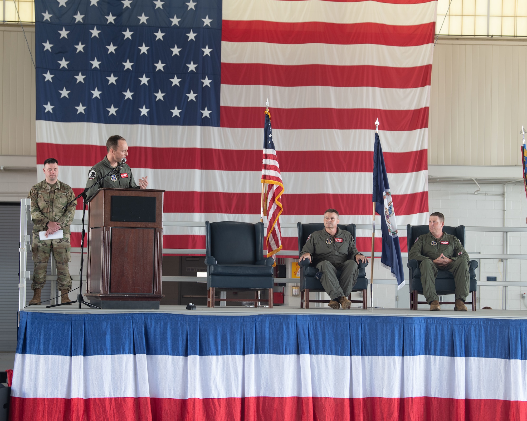 Four military members on stage with Col. Brock E. Lange, 192nd Wing commander at the podium