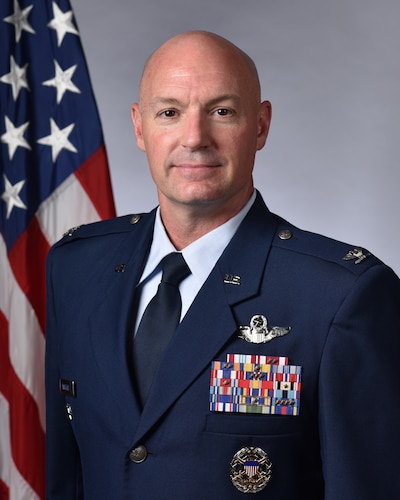 A photo of a man next to the US flag.