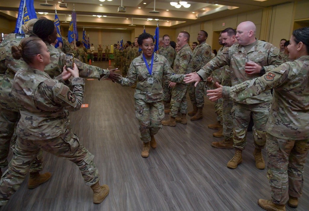 A woman in military uniforms gives high-fives to people