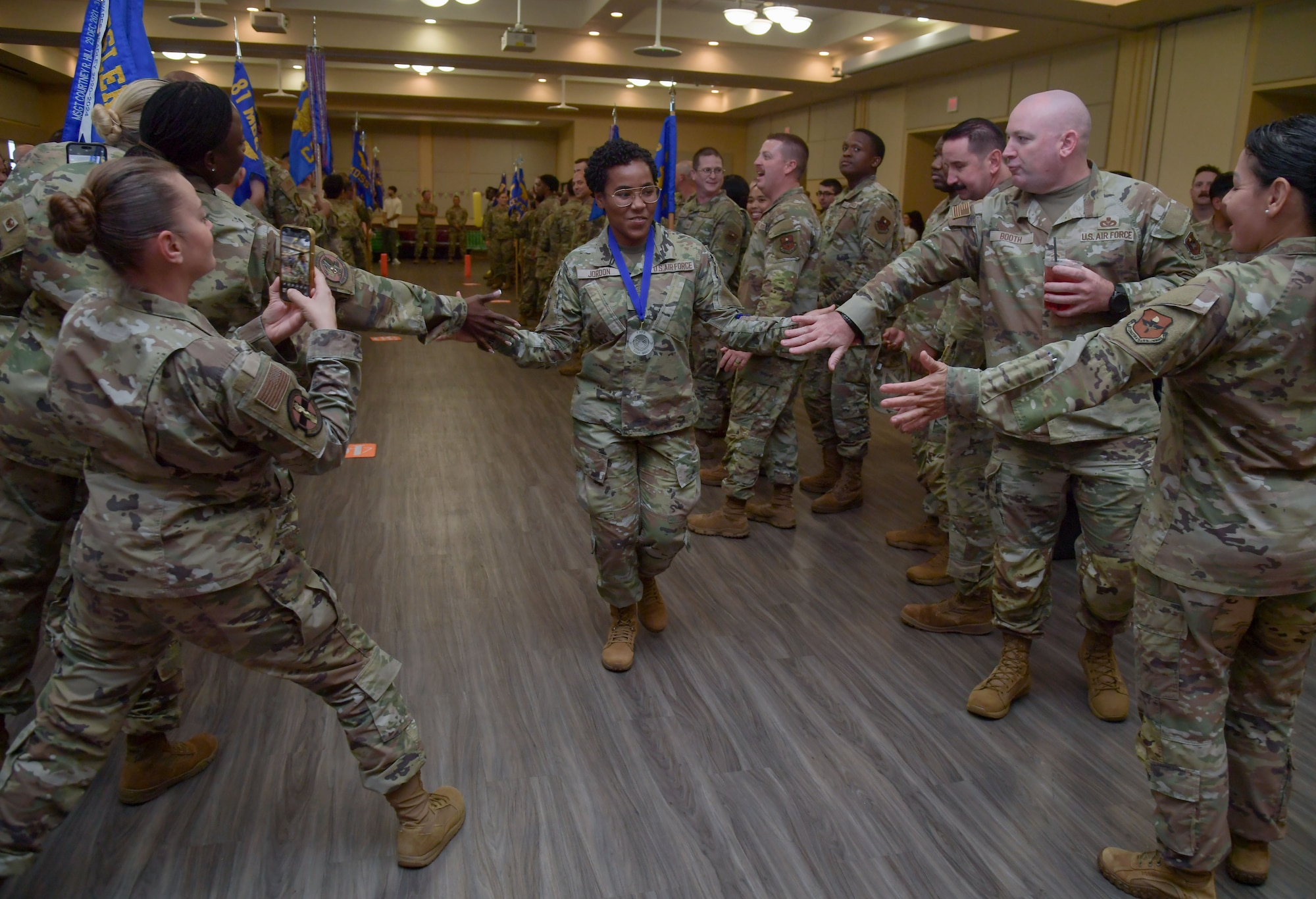 A woman in military uniforms gives high-fives to people
