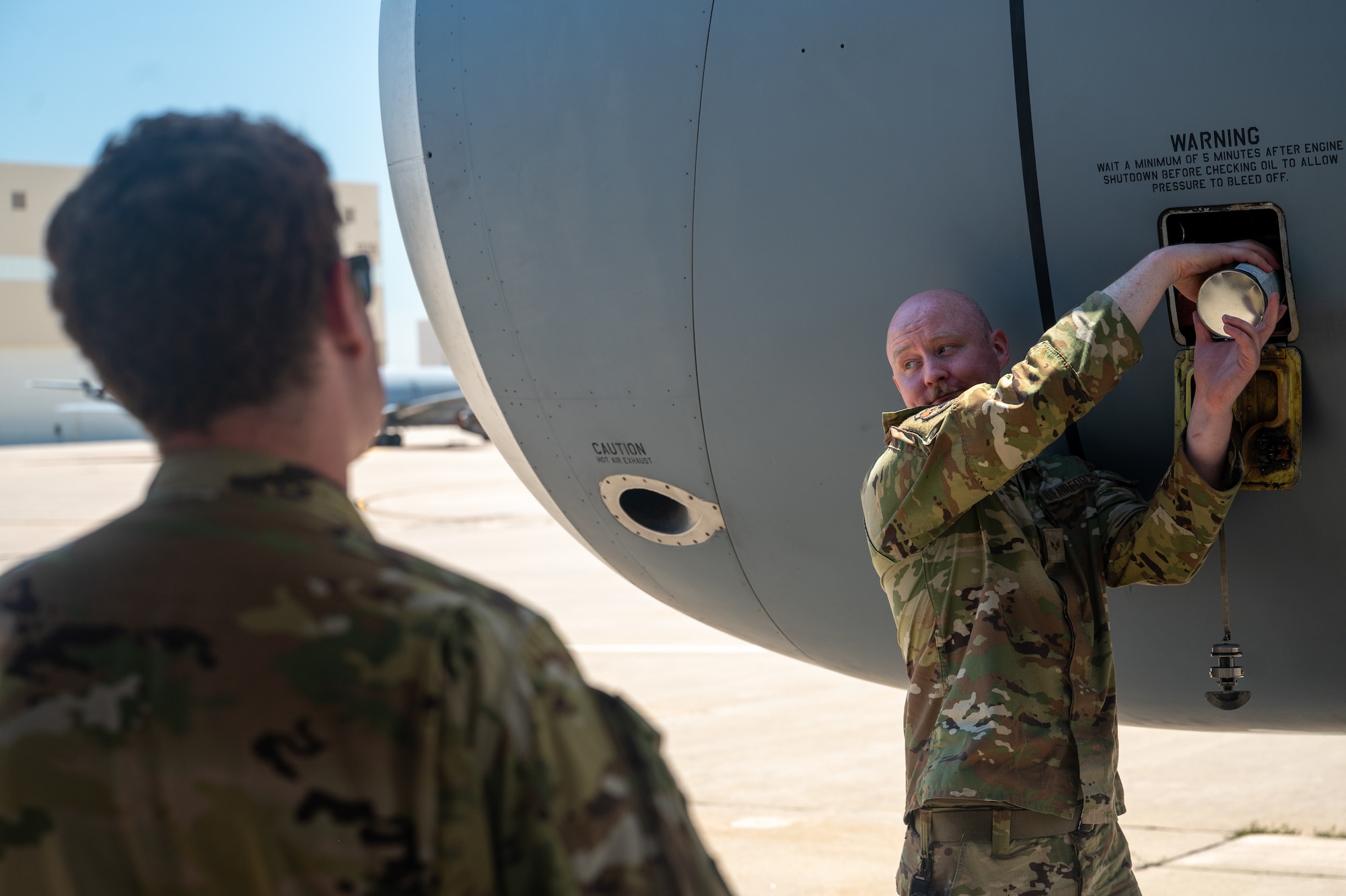 U.S. Air Force Senior Airman Allen White, 722nd Aircraft Maintenance Squadron crew chief, demonstrates procedures for servicing the engine oil of a KC-135 Stratotanker aircraft to pilots and boom operators assigned to the 22nd Air Refueling Wing at McConnell Air Force Base, Kansas, July 8, 2025. The operators were instructed on basic maintenance procedures as they provided critical air refueling support to the Air Force's 2025 Department-Level Exercise series. The DLE series encompasses all branches of the Department of Defense, along with Allies and partners, employing more than 400 Joint and coalition aircraft and more than 12,000 members at more than 50 locations across 3,000 miles (U.S. Air Force photo by Tech. Sgt. Nathan Eckert)