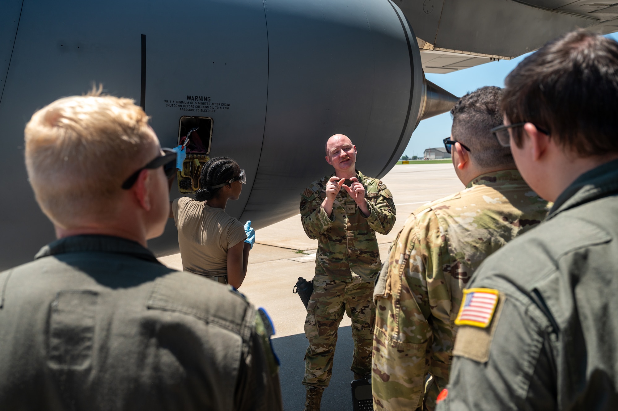 U.S. Air Force Senior Airman Allen White, 722nd Aircraft Maintenance Squadron crew chief, demonstrates procedures for servicing the engine oil of a KC-135 Stratotanker aircraft to pilots and boom operators assigned to the 22nd Air Refueling Wing at McConnell Air Force Base, Kansas, July 8, 2025. The operators were instructed on basic maintenance procedures as they provided critical air refueling support to the Air Force's 2025 Department-Level Exercise series. The DLE series encompasses all branches of the Department of Defense, along with Allies and partners, employing more than 400 Joint and coalition aircraft and more than 12,000 members at more than 50 locations across 3,000 miles (U.S. Air Force photo by Tech. Sgt. Nathan Eckert)