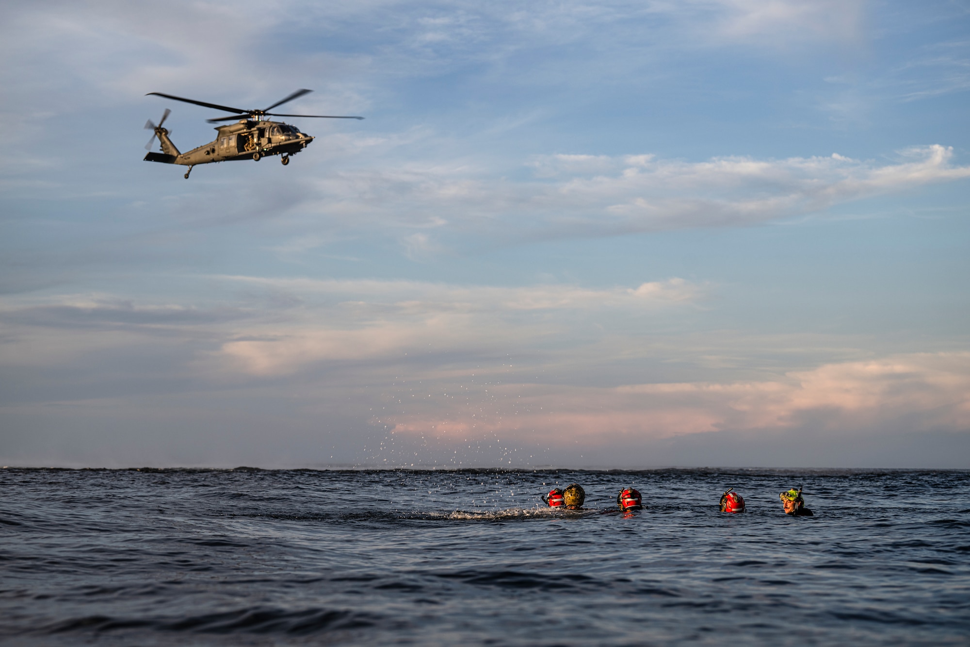 photo depicting people treading in open water with helicopter overhead