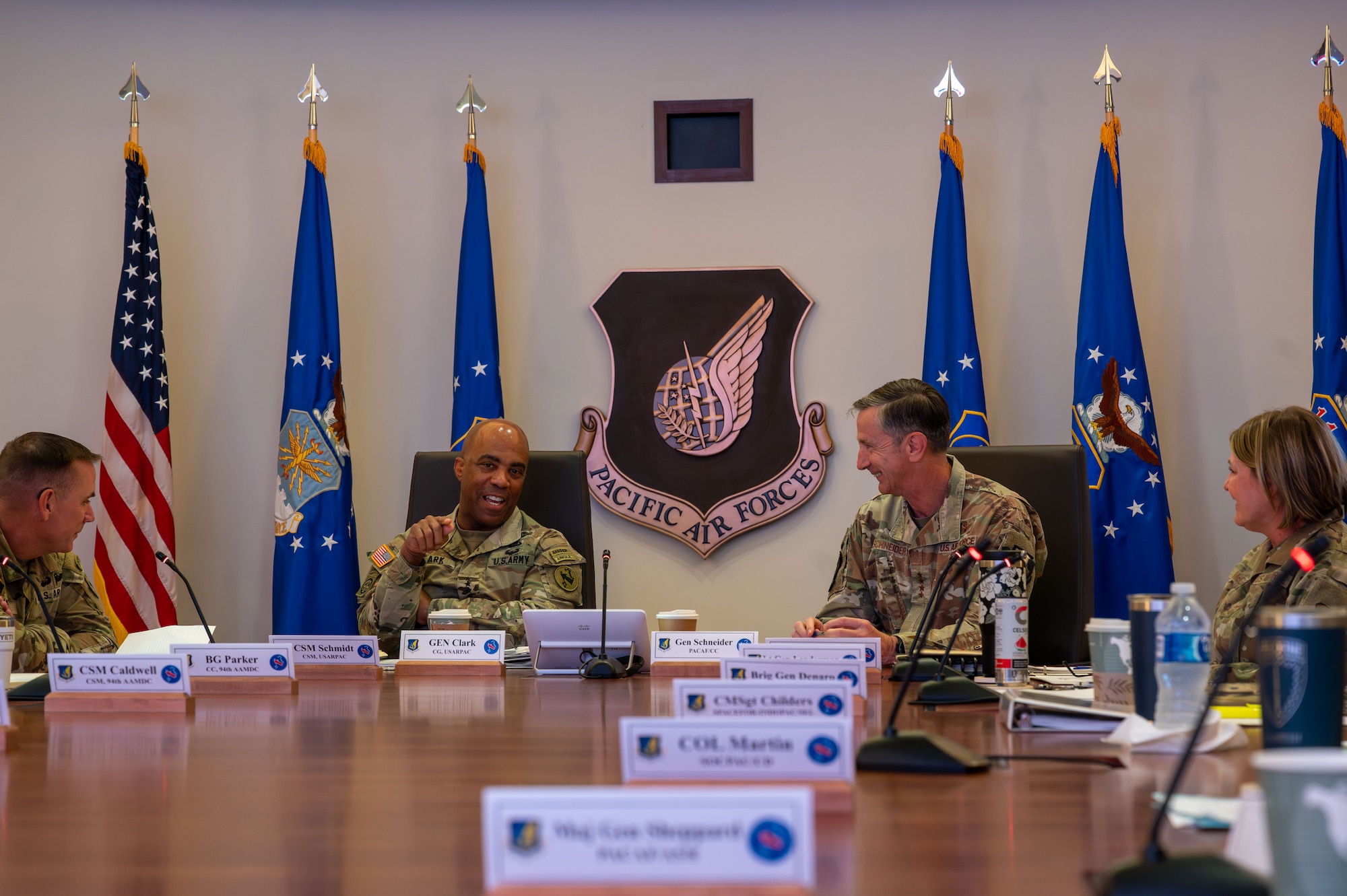 U.S. Air Force Gen. Kevin Schneider, Pacific Air Forces commander, and U.S. Army Gen. Ronald Clark, U.S. Army Pacific commander, hosted the next iteration of the Cross-Component Integration Forum to discuss strategies and best practices for fostering greater interoperability and integration among the U.S. Army and Air Force units in the Indo-Pacific at Joint Base Pearl Harbor-Hickam, Hawaii, Aug. 19, 2025. This collaboration is essential for cohesive joint operations, especially in implementing Agile Combat Employment (ACE) and Multi-Domain Operations (MDO). (U.S. Air Force photo by Staff Sgt. Elizabeth Taranto)

The two leaders are seated at a large table alongside other leaders in their commands.