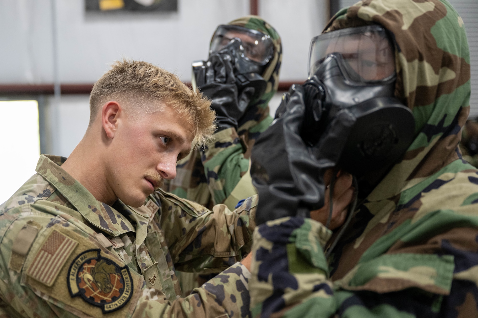 An Airman assists another airman wearing a C.B.R.N. suit.