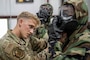 An Airman assists another airman wearing a C.B.R.N. suit.