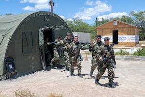 Airmen walk outside from a green military style tent.