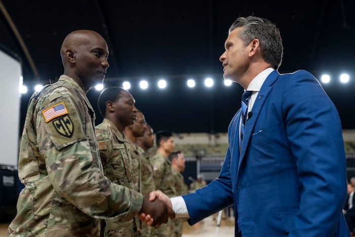 Defense Secretary Pete Hegseth shakes hands with one of several guardsmen in a line.