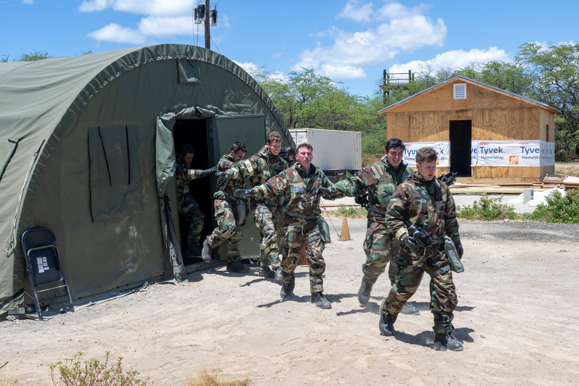Airmen walk outside from a green military style tent.