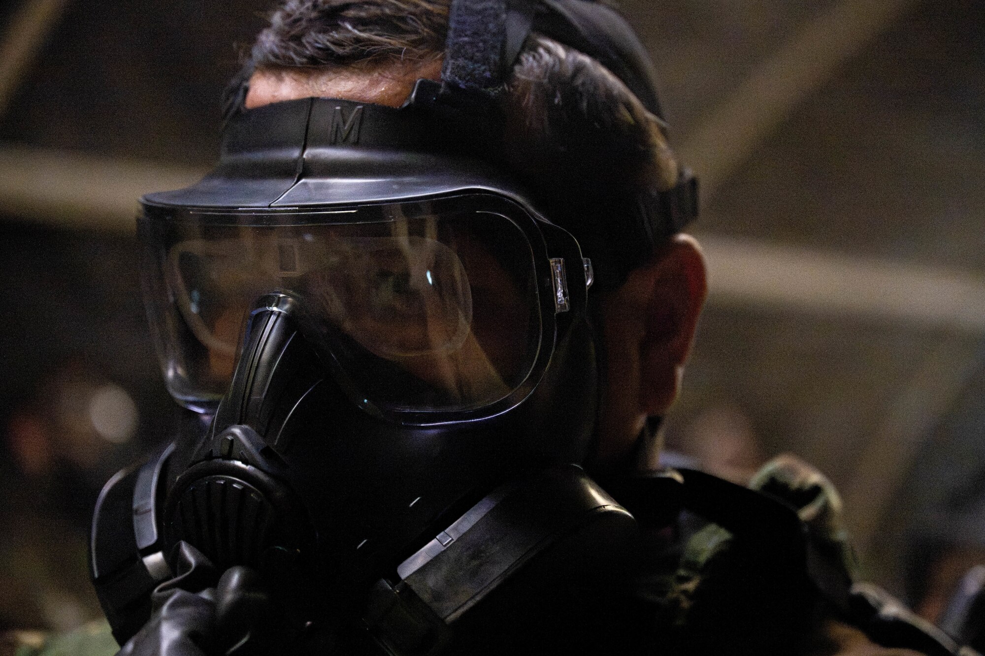 Airman wears a gas mask inside a tent.