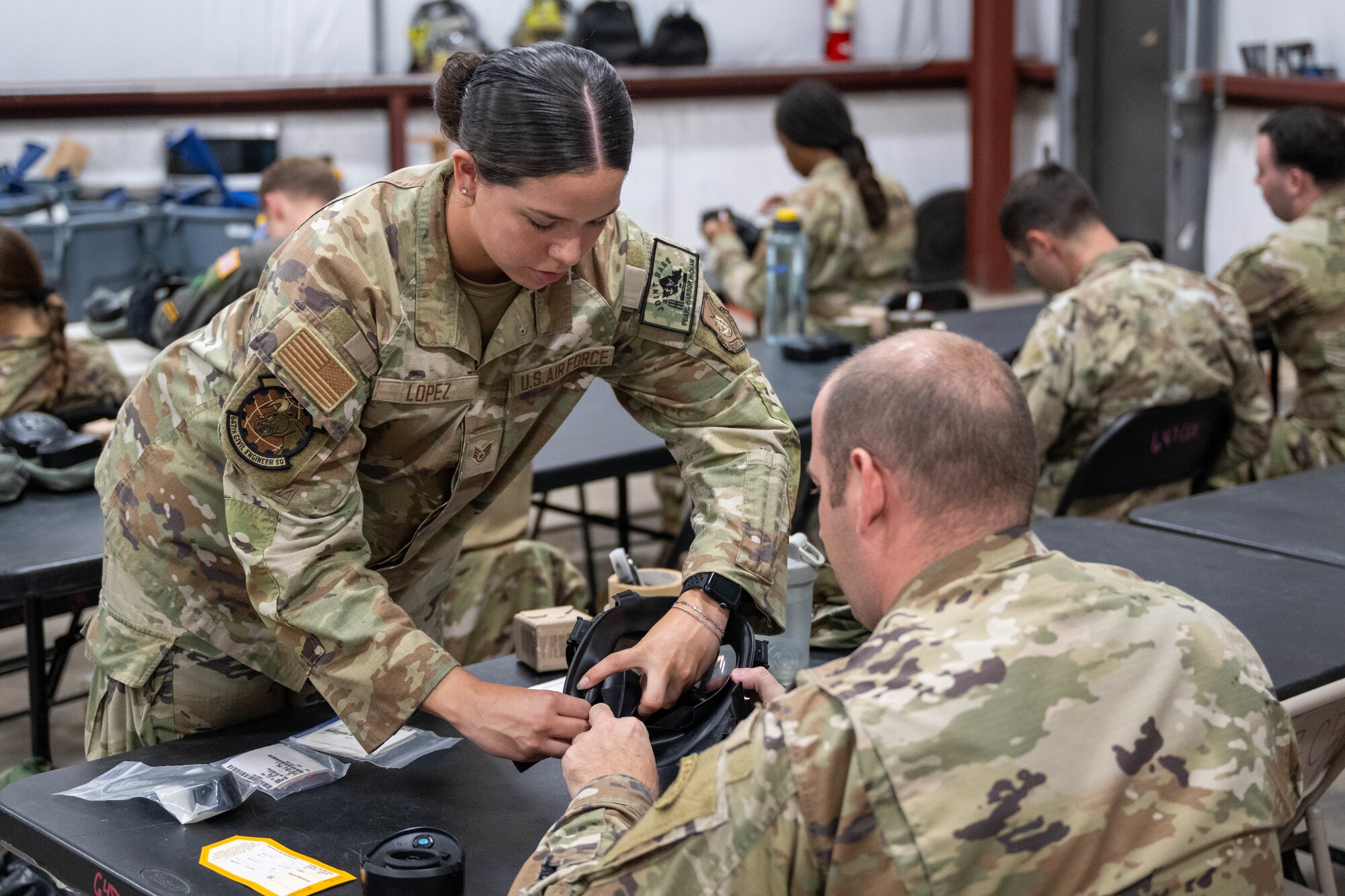 An Airman helps another Airman with dismantling his gasmask.