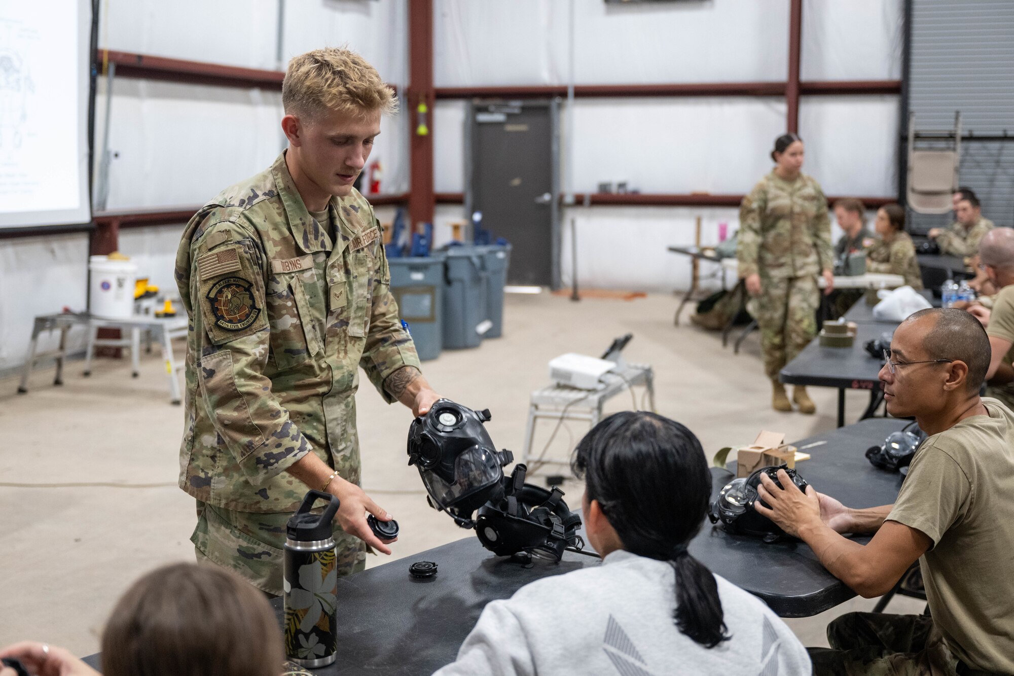U.S. Air Force Airman 1st Class William Dobyns, 647th Civil Engineer Squadron emergency management journeyman, teaches Airmen how to dismantle their assigned gas masks during a chemical, biological, radiological and nuclear defense course on Joint Base Pearl Harbor-Hickam, Hawaii, August 21, 2025. In emergency management, CBRN specialists  perform response operations, warning and reporting to support critical missions, ensuring the safety and security of personnel and equipment. (U.S. Air Force photo by Airman 1st Class Aden Brown)