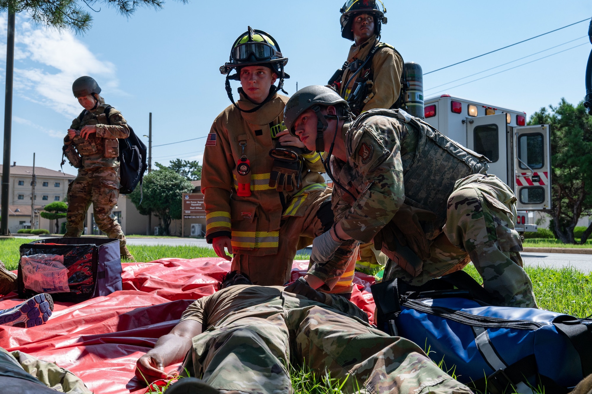 A combat medic tends to someone next to a firefighter