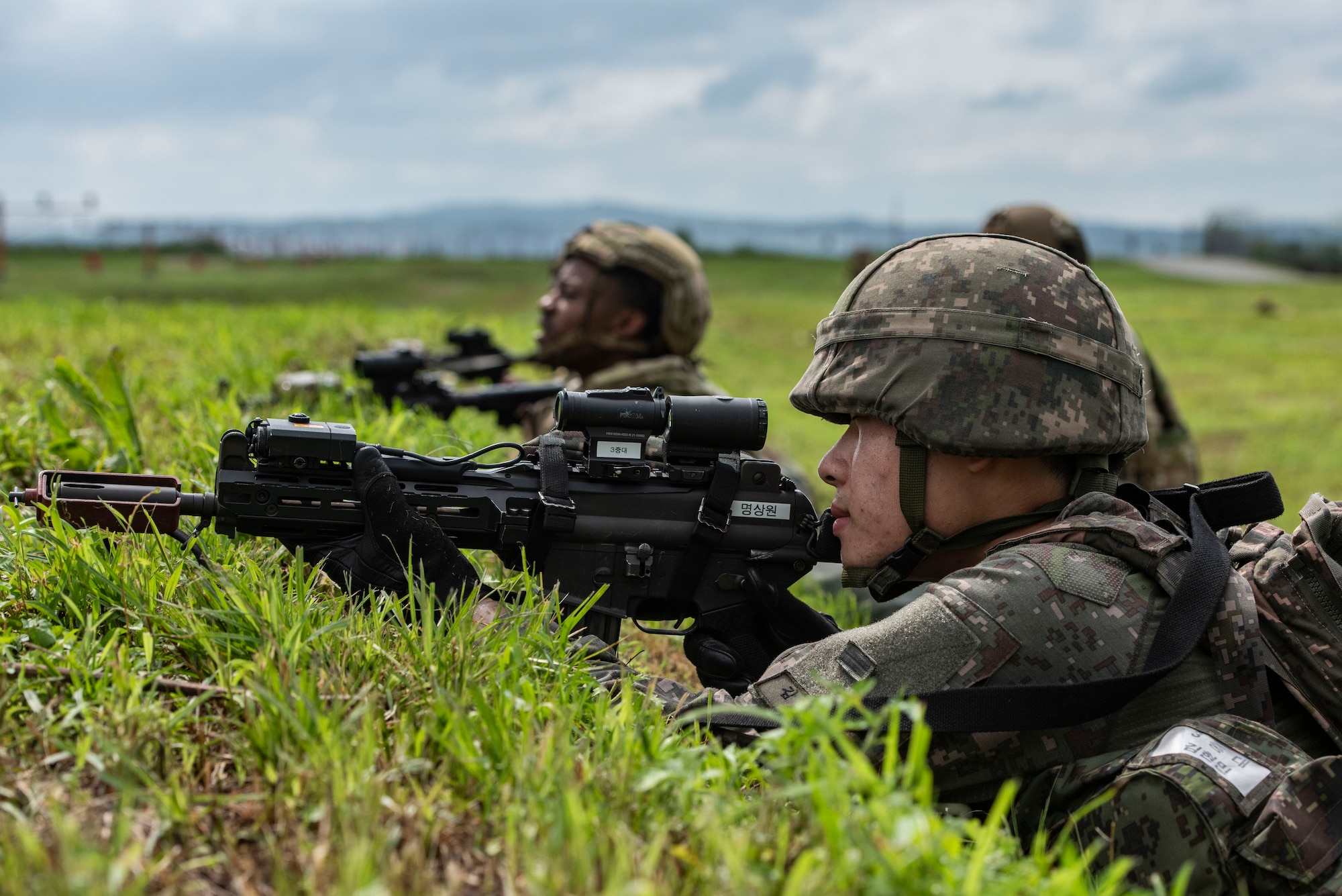 A Republic of Korea Air Force airman takes a
defensive position alongside 51st Fighter Wing
Airmen while responding to a simulated ground attack
during Ulchi Freedom Shield 25 at Osan Air Base,
Republic of Korea, Aug. 19, 2025.