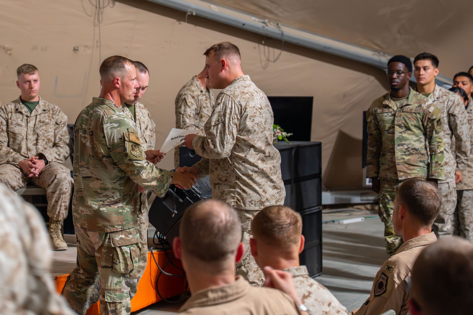 U.S. Air Force Chief Master Sgt. Christopher Griste, 378th Air Expeditionary Wing command chief, presents a certificate to a Marine