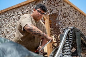 U.S. Air Force Staff Sgt. Antonio Mendoza, 378th Expeditionary Maintenance Squadron armament floor supervisor, uses a hand crank to conduct an operations check on a Universal Ammunition Loading System.