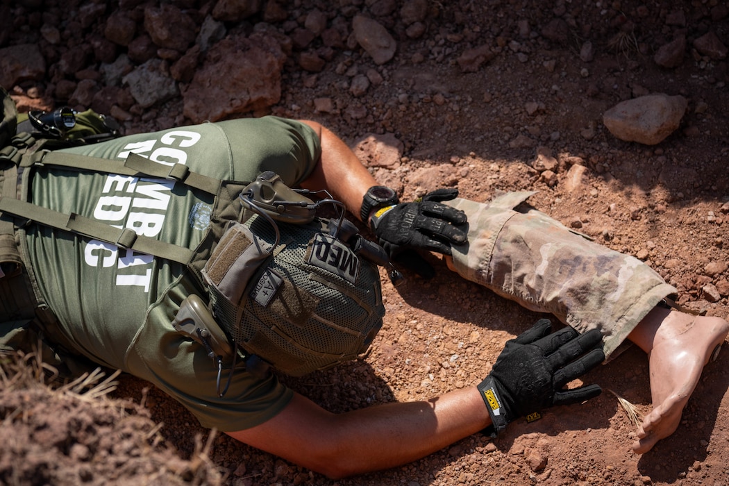 A person crawls through a muddy trench and grabs a plastic leg.