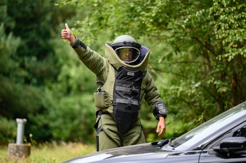 A person wearing a bomb suit gives a thumbs-up sign.