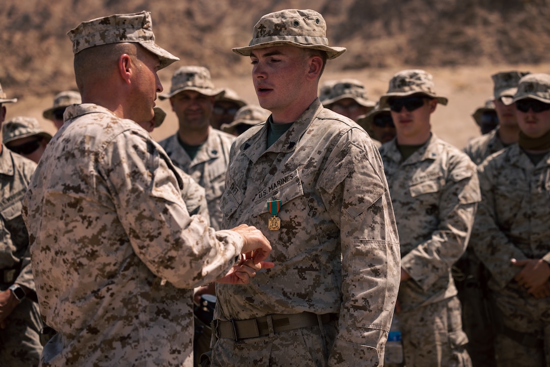 U.S. Marine Corps Brig. Gen. Matthew S. Reid, commanding general of Naval Amphibious Force, Task Force 51/5th Marine Expeditionary Brigade, left, pins a Navy and Marine Corps Achievement Medal on Cpl. Evan Swift, a fire team leader with Charlie Company, 4th Law Enforcement Battalion, Force Headquarters Group, Marine Forces Reserve, on Camp Titin, Jordan, May 18, 2024. Swift was recognized for his exceptional work and personal progress while training in Jordan. (U.S. Marine Corps photo by Lance Cpl. Joaquin Dela Torre)