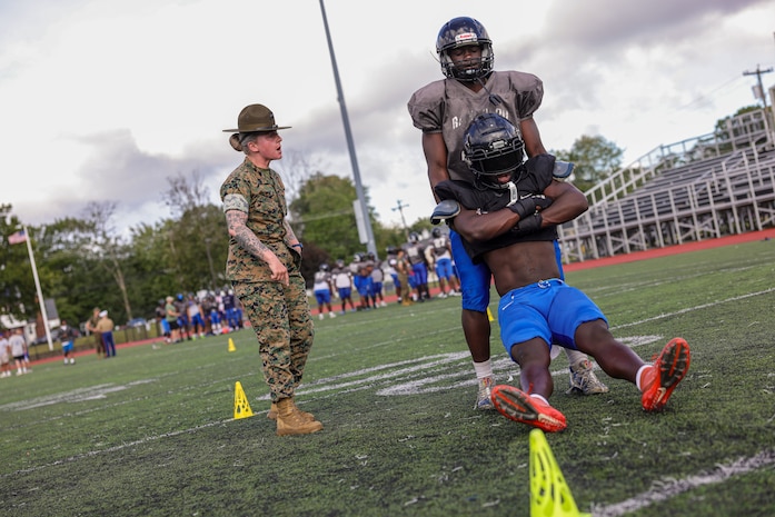 U.S. Marine Corps Sgt. Shannon Ruddy, a drill instructor with Mike Company, 3rd Recruit Training Battalion, Marine Corps Recruit Depot Parris Island, and a Blairstown, New Jersey native, directs a Randolph High School football player during a Marine Corps combat fitness test as part of Marine Week Boston, Aug. 21, 2025. During Marine Week Boston, Marines with Marine Corps Recruiting Command shared Marine Corps traditions with local high schools in honor of the Corps’ 250th birthday. Marines stationed across the globe commemorate the 250th anniversary of the Marine Corps, honoring a distinguished legacy of service, sacrifice, and unwavering fidelity to both the nation and fellow Marines. (U.S. Marine Corps photo by Sgt. Aidan Hekker)