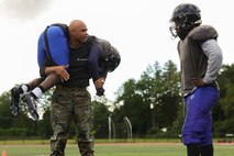 U.S. Marine Corps Capt. Edgardo Diaz, the executive officer of Recruiting Station Boston, demonstrates a fireman’s carry to a Randolph High School football player during a Marine Corps combat fitness test as part of Marine Week Boston, Aug. 21, 2025. During Marine Week Boston, Marines with Marine Corps Recruiting Command shared Marine Corps traditions with local high schools in honor of the Corps’ 250th birthday. Marines stationed across the globe commemorate the 250th anniversary of the Marine Corps, honoring a distinguished legacy of service, sacrifice, and unwavering fidelity to both the nation and fellow Marines. (U.S. Marine Corps photo by Sgt. Aidan Hekker)