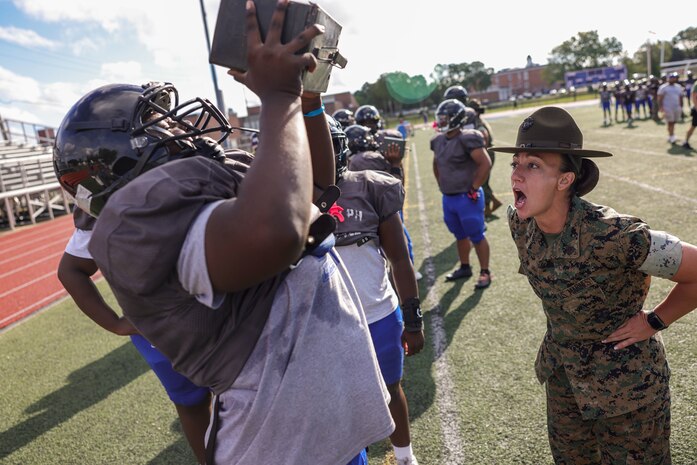 U.S. Marine Corps Sgt. Elizabeth McSparin, a drill instructor and Marine Corps Instructor of Water Survival with Bravo Company, 1st Recruit Training Battalion, Marine Corps Recruit Depot Parris Island, and Rock Island, Illinois native, motivates a Randolph High School football player during a Marine Corps combat fitness test as part of Marine Week Boston, Aug. 21, 2025. During Marine Week Boston, Marines with Marine Corps Recruiting Command shared Marine Corps traditions with local high schools in honor of the Corps’ 250th birthday. Marines stationed across the globe commemorate the 250th anniversary of the Marine Corps, honoring a distinguished legacy of service, sacrifice, and unwavering fidelity to both the nation and fellow Marines. (U.S. Marine Corps photo by Sgt. Aidan Hekker)