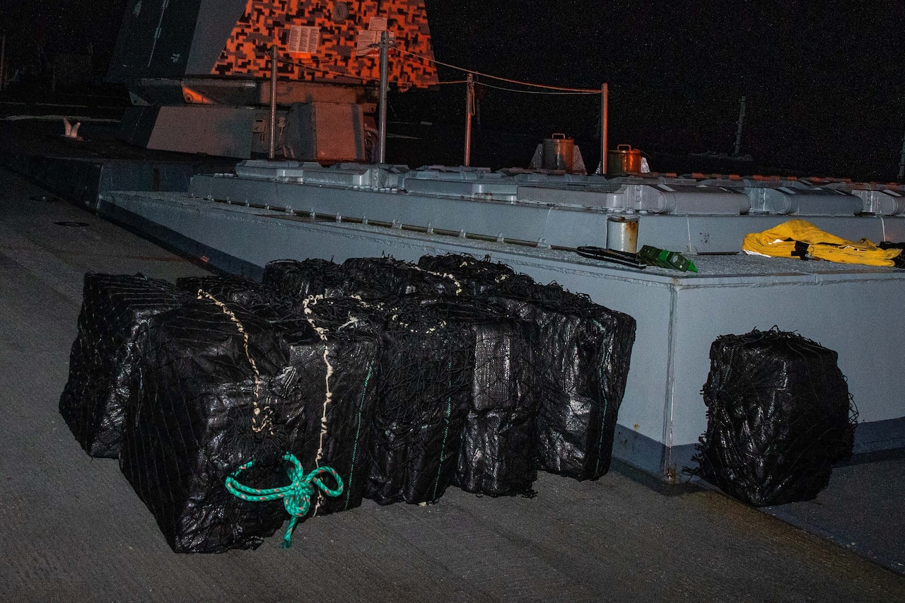 Large bales wrapped in black plastic are stacked together on a ship.