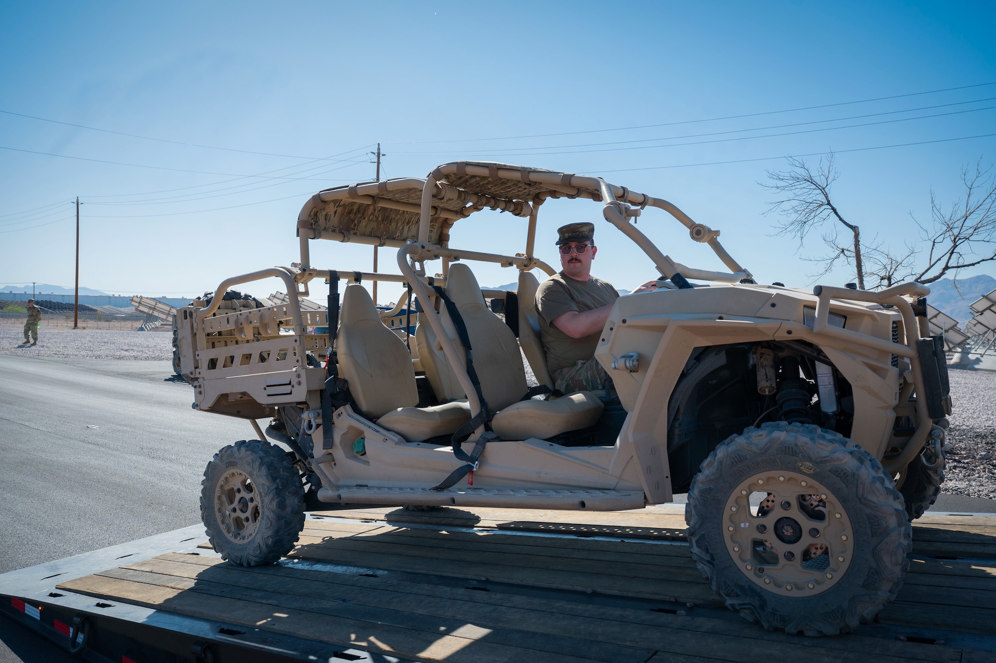 An Airman drives a utility vehicle off a trailer.