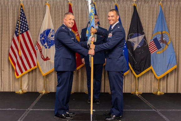 A colonel passes a flag to a lieutenant colonel