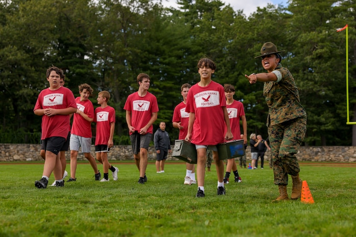 U.S. Marine Corps Sgt. Julie Leon, left, a drill instructor Golf Company, 2nd Recruit Training Battalion, Marine Corps Recruit Depot Parris Island, and a Los Angeles, California native, directs a Hudson High School football player during the Marine Corps combat fitness test as part of Marine Week Boston, Aug. 21, 2025. During Marine Week Boston, Marines with Marine Corps Recruiting Command shared Marine Corps traditions with local high schools in honor of the Corps’ 250th birthday. Marines stationed across the globe commemorate the 250th anniversary of the Marine Corps, honoring a distinguished legacy of service, sacrifice, and unwavering fidelity to both the nation and fellow Marines. (U.S. Marine Corps photo by Sgt. Aidan Hekker)