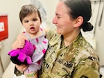 Female Soldier holding her young daughter in a clinic treatment room.