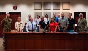 U.S. Air Force Col. Matthew Norton, 17th Training Wing commander, and Chief Master Sgt. Derek Neill, 17th TRW command chief, pose for a group photo with the 2025-2026 honorary commanders during the Wing Staff Agency immersion at the judge advocate court room inside the Norma Brown building, Goodfellow Air Force Base, Texas, Aug. 21, 2025. The WSA immersion was given to explain and showcase the various agencies that support Airmen from the background at Goodfellow. (U.S. Air Force photo by Airman 1st Class Brian Lummus)