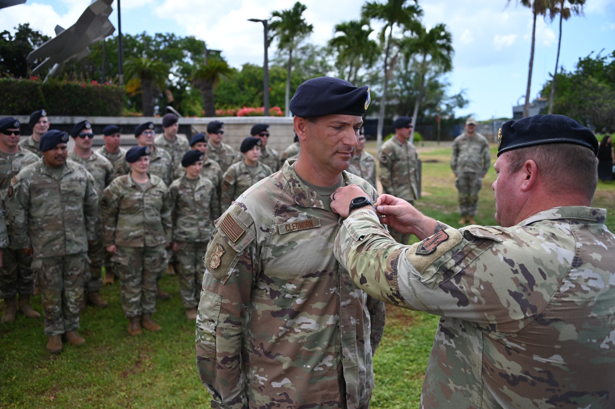 A group of airmen in OCP uniforms stand in formation as their commander pins a badge upon their senior enlisted leader